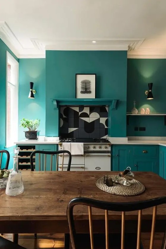 a teal kitchen with chic cabinets and matching walls for a sleek look, white stone countertops and a dining zone with vintage furniture