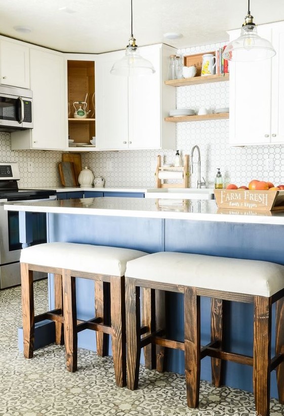 a tow-tone kitchen with white upper and blue lower cabinets, white countertops, white upholstered stools and pendant lamps