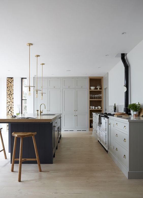a traditional dove grey kitchen, a navy kitchen island with a wooden countertop and wooden stools to match it