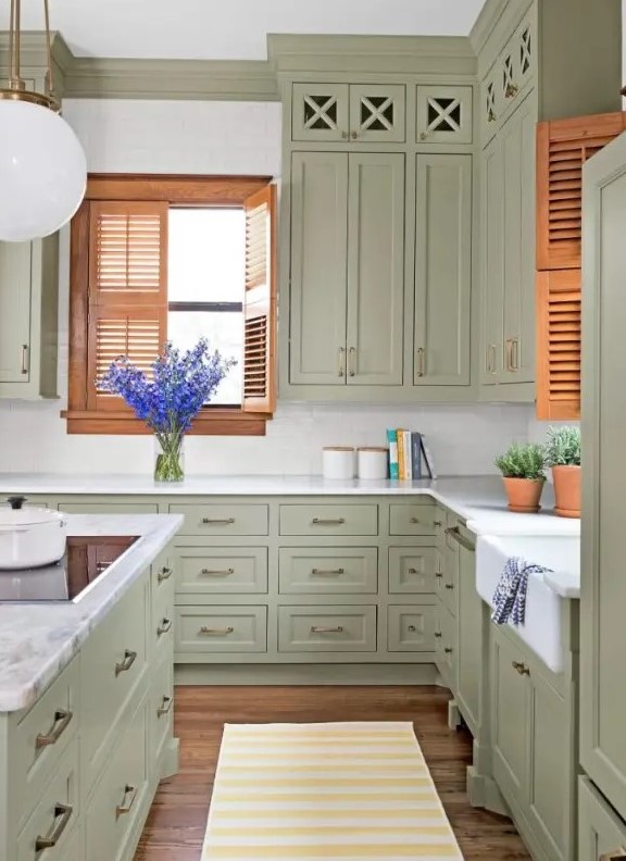 a vintage sage green kitchen with shaker cabinets, a white subway tile backsplash and stone countertops and brass handles