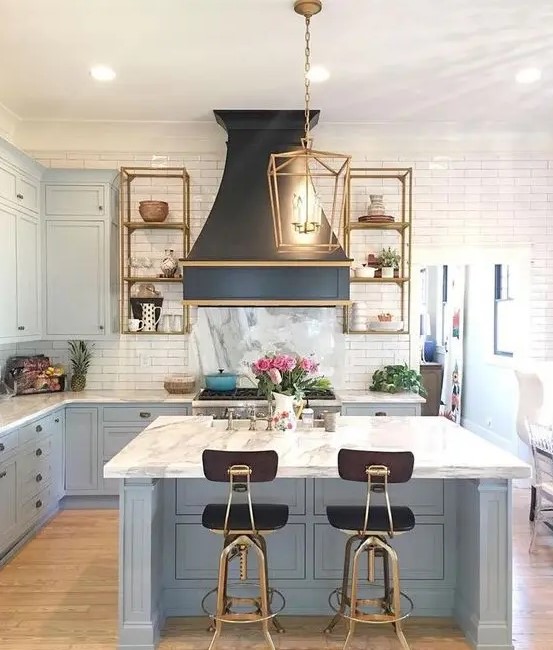 an art deco kitchen with powder blue cabinets and a kitchen island completed with a white stone countertop and a tile backsplash