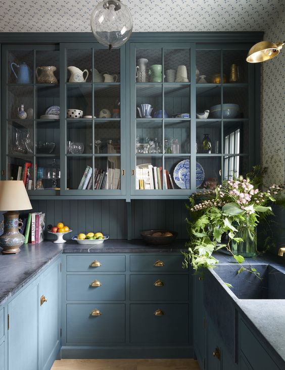 an elegant and refined kitchen with blue cabinets, grey stone countertops, a shiplap backsplash, gold handles and knobs