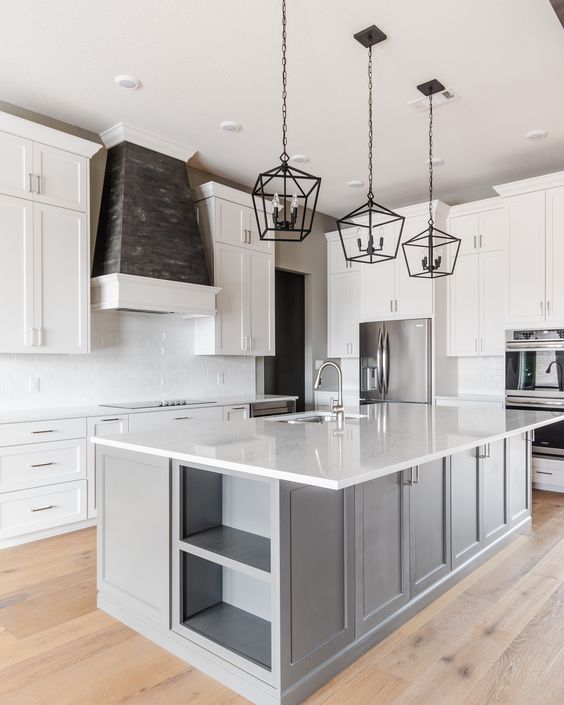 an elegant farmhouse kitchen with white cabinets, a grey kitchen island, white countertops and a backsplash, black frame pendant lamps