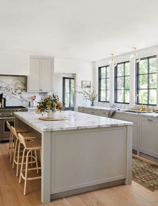 an inspiring dove grey modern country kitchen with shaker style cabients, white marble countertops, gold touches and rattan stools