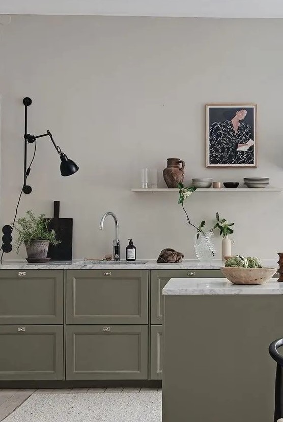 an olive green kitchen with shaker cabinets, white stone countertops, an open shelf, a black sconce and black touches