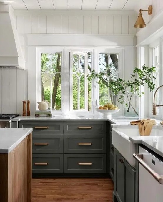 an olive green lower cabinet kitchen with white stone countertops, white beadboard walls and brass and gold fixtures