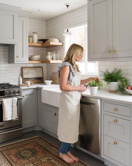 dove grey cabinets, a white tile backsplash and white countertops, wooden shelves and a boho rug for a chic look