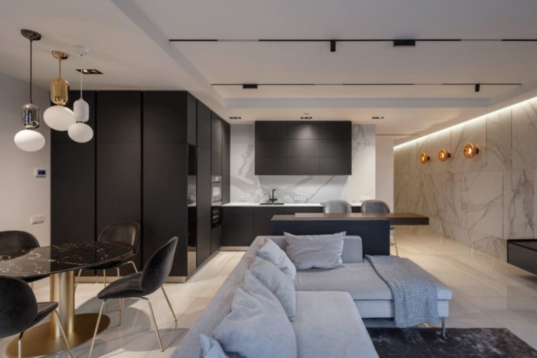 The kitchen is sleek and black, with a marble wall, and the dining space is done with a black marble table to echo with it The kitchen is sleek and black, with a marble wall, and the dining space is done with a black marble table to echo with it