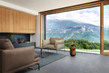 03 The living room shows off amazing views of the slopes, it’s done with sleek black surfaces and wood, the furniture is contemporary