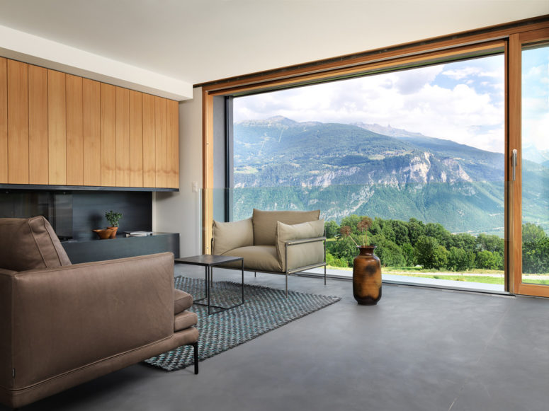 The living room shows off amazing views of the slopes, it's done with sleek black surfaces and wood, the furniture is contemporary