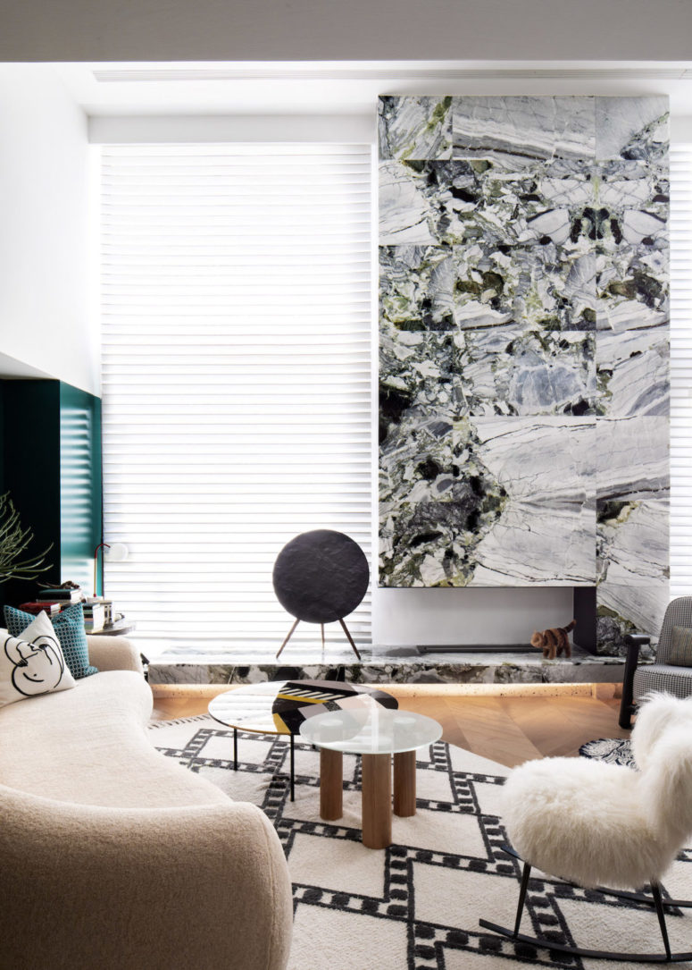 The living room shows off an amazing stone clad fireplace, a comfy curved sofa, trendy furniture and a wardrobe in the corner