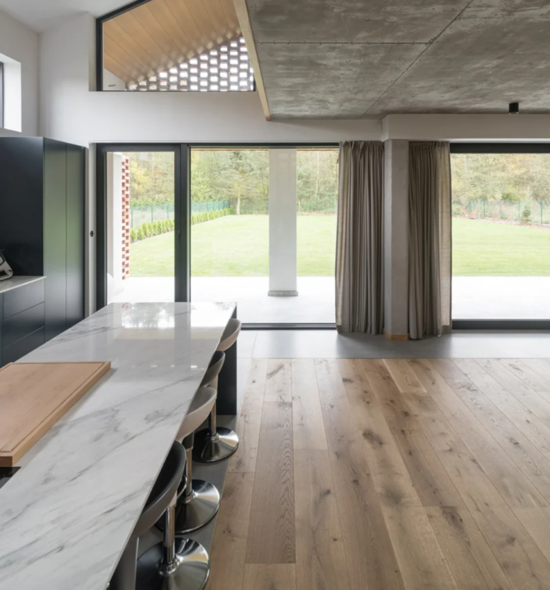 The kitchen is done with dark sleek cabinets, white stone countertops, a large island for cooking and eating here, too