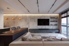 04 The living room is done with comfortable modern furniture, white marble on the wall and a dark TV unit