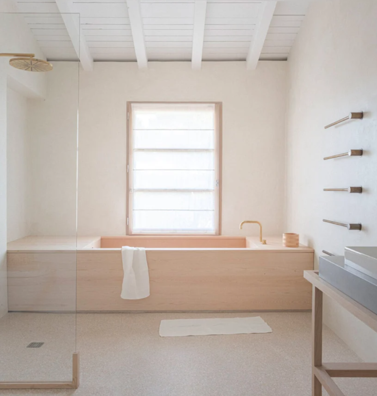 a minimalist bathroom with white walls and wood clad tub