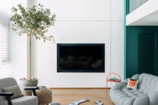 05 This is another sittign room, with a catchy soft sofa, a built-in TV, layered rugs and a potted tree