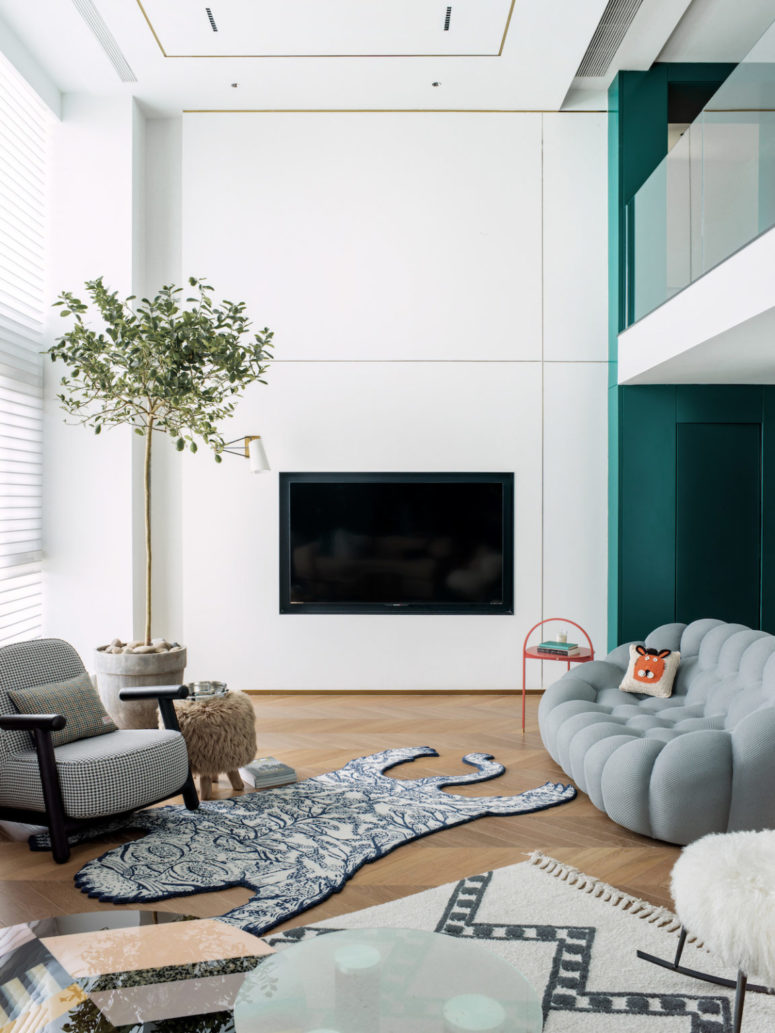 This is another sittign room, with a catchy soft sofa, a built-in TV, layered rugs and a potted tree