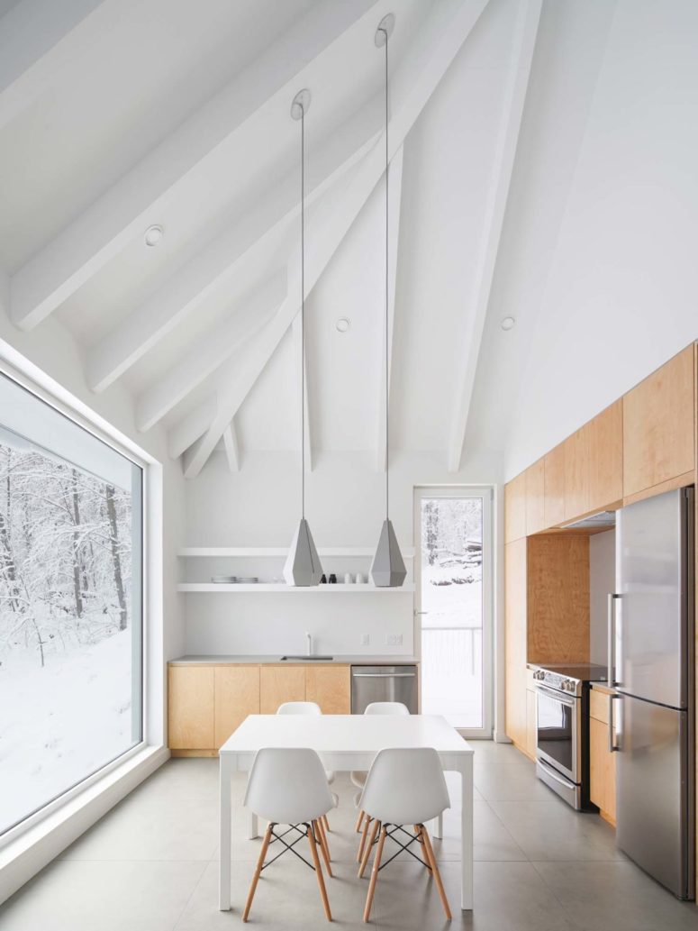 The kitchen is united with the dining space, there's open shelving, a small and sleek dining set and catchy geometric pendant lamps