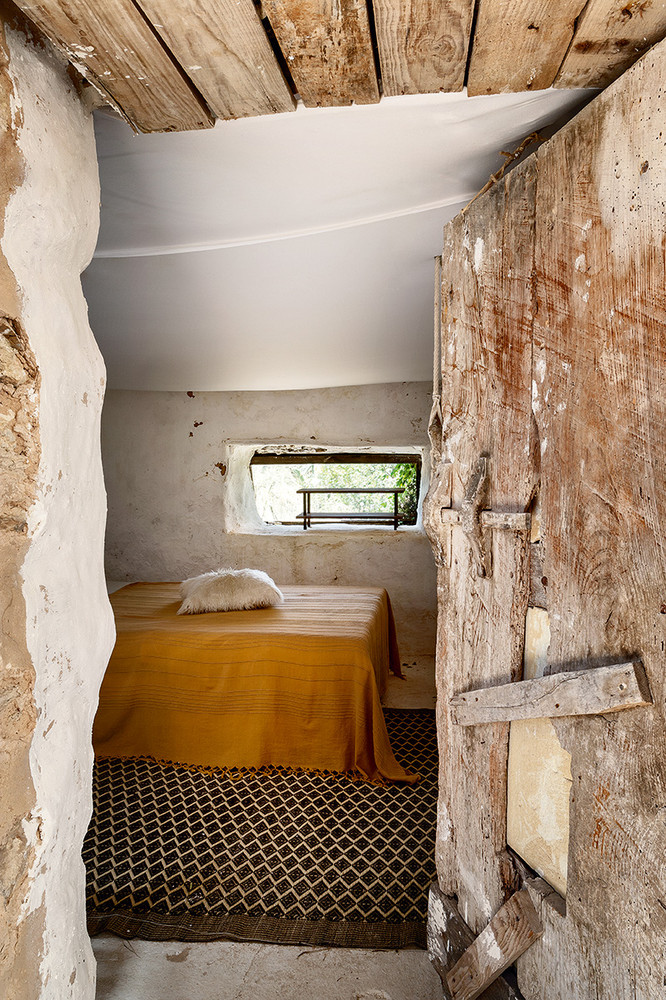 The second bedroom is done with bright printed textiles, a low bed and a small window