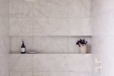 08 The small bathroom features a shower space clad with white marble tiles