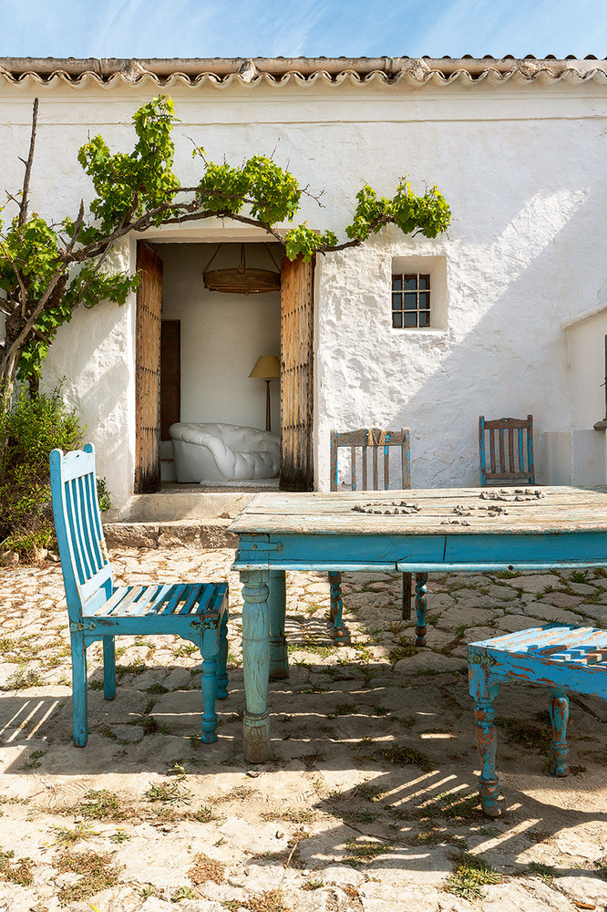 There's an outdoor dining space with blue shabby chic furniture and a tree growing here