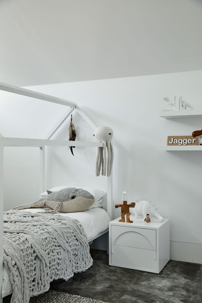 Another kid bedroom is also white, with a house-shaped bed and fun toys all around