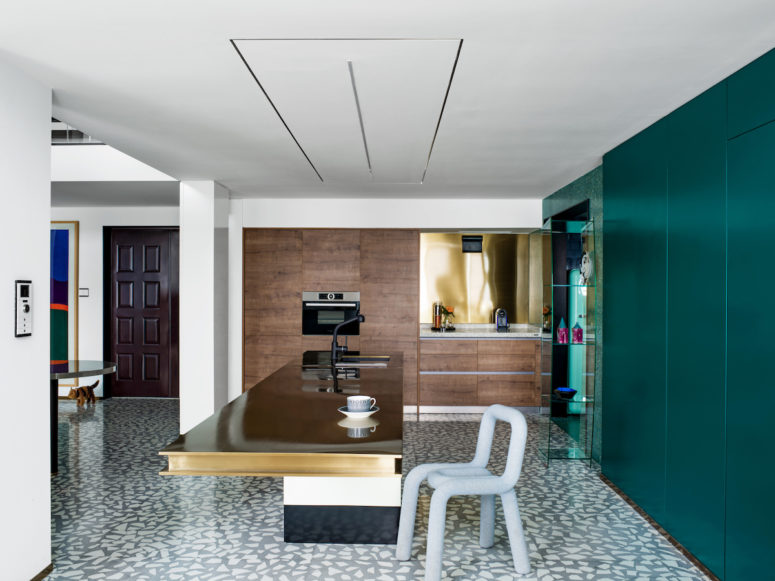 There are also wooden cabinets with built-in appliances and a polished gold backsplash