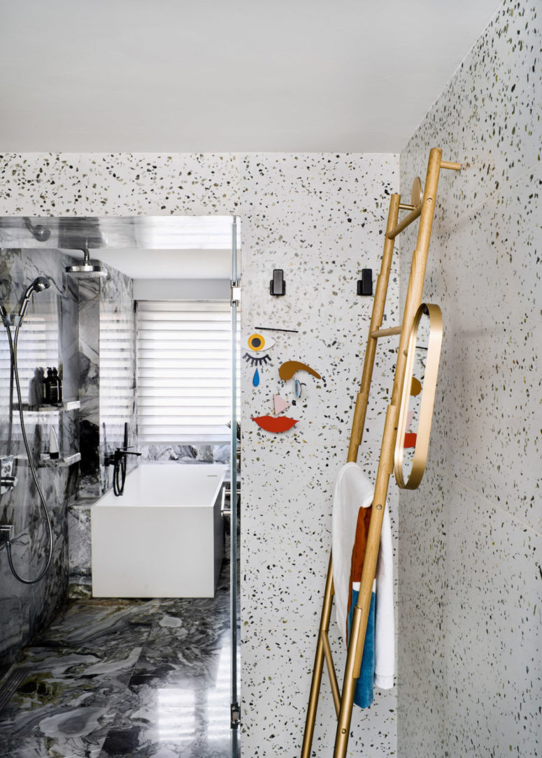 The master bathroom is done with terrazzo and grey marble tiles, with modern fixtures and touches of gold