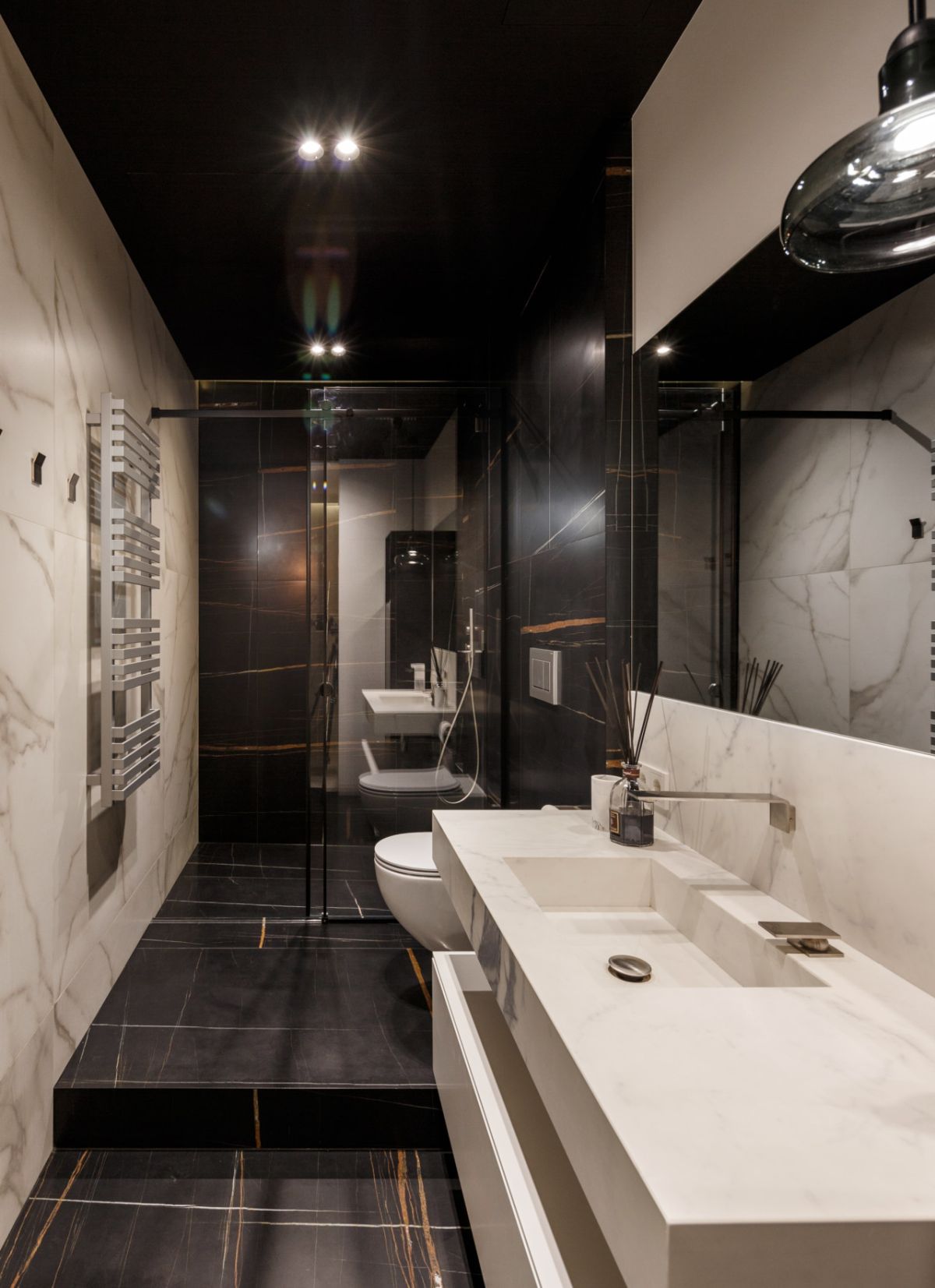 The second bathroom is clad with black marble and features a white marble sink and vanity in one