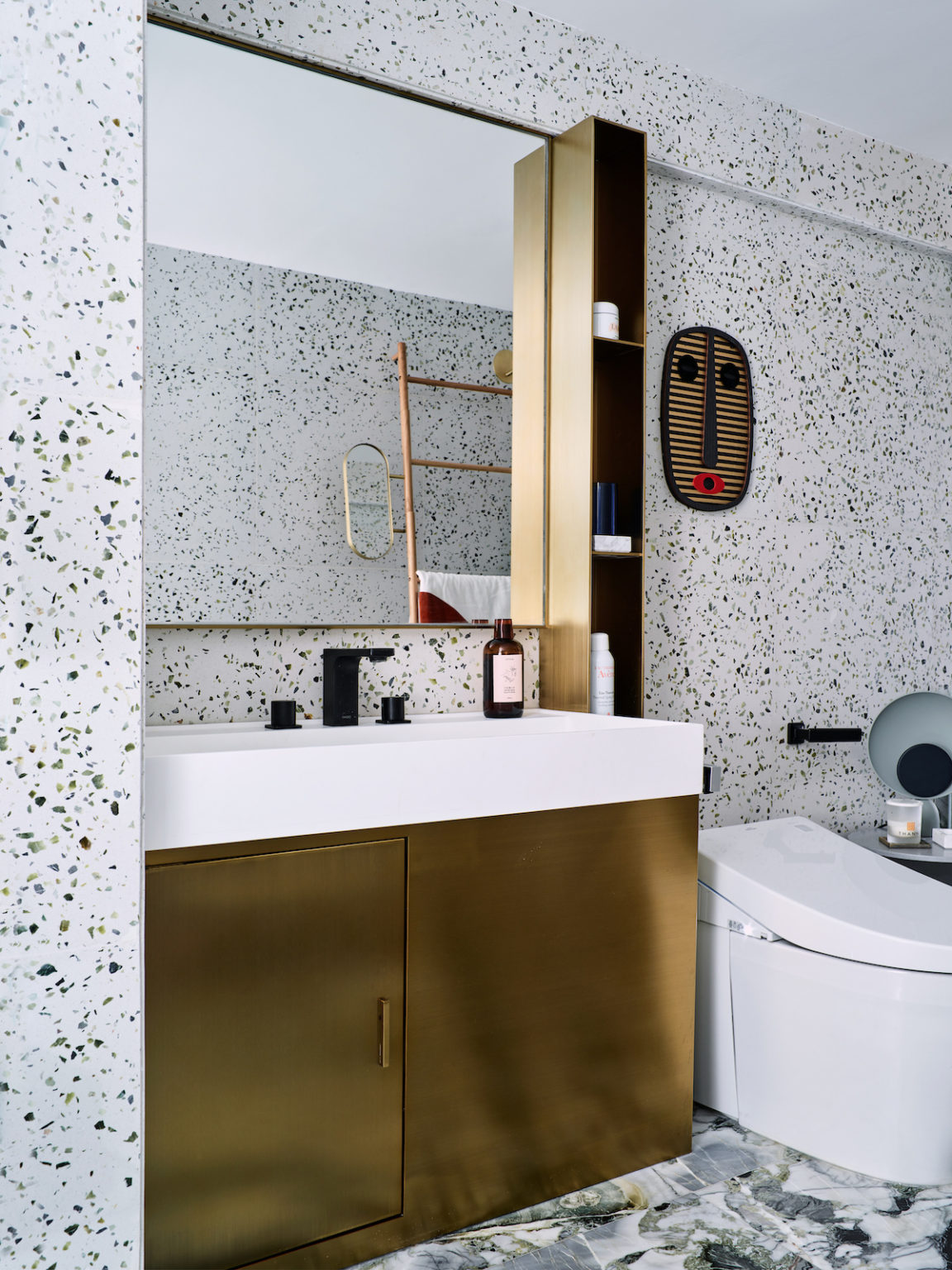 The gold vanity and a small shelf add to the look of the bathroom