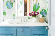 14 a bright bthroom with colorful and whimsical wallpaper, a blue vanity and bright blooms in a white vase