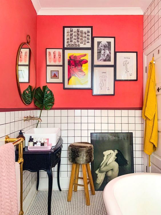 a unique bathroom with red walls, white tiles, pink and mustard textiles and quirky furniture and artworks