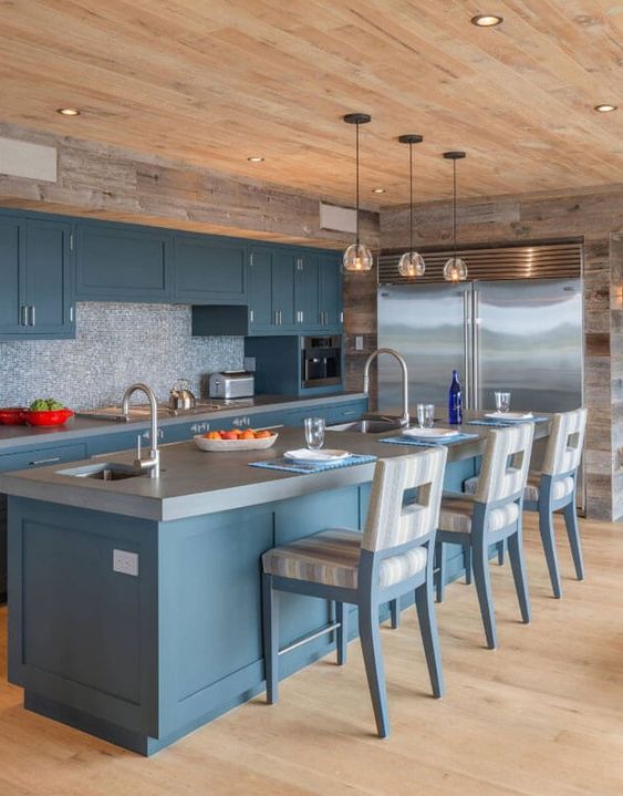 a beautiful blue kitchen with a mosaic backsplash, a concrete countertop, a wooden ceiling and reclaimed wood on the walls