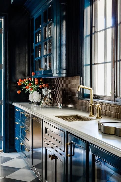 a bold blue vintage kitchen with brown mosaic tiles on the backsplash plus touches of gold for a shiny look