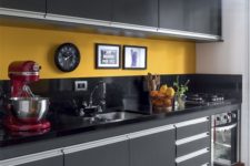 a bold kitchen done with black cabinets and countertops plus a bold yellow backsplash looks wow
