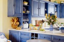 a bright blue and light yellow kitchen refreshed with white surfaces and with light-colored natural wood
