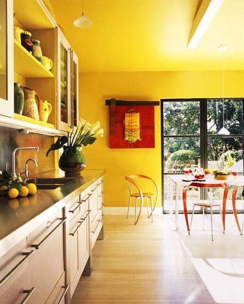 a bright yellow kitchen with neutral cabinets and black countertops plus bold red artworks looks ultimate