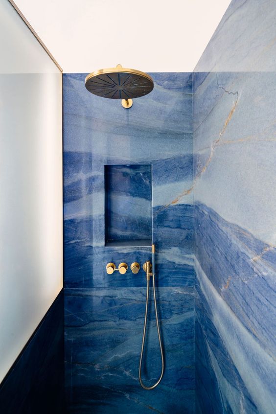 a catchy and bold blue bathroom done with watercolor tiles, gold fixtures and lamps is a stylish space