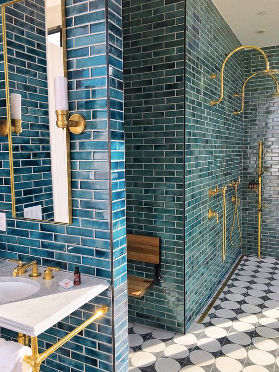 a catchy bathroom clad with blue tiles, finished off with gold fixtures and sconces looks wow