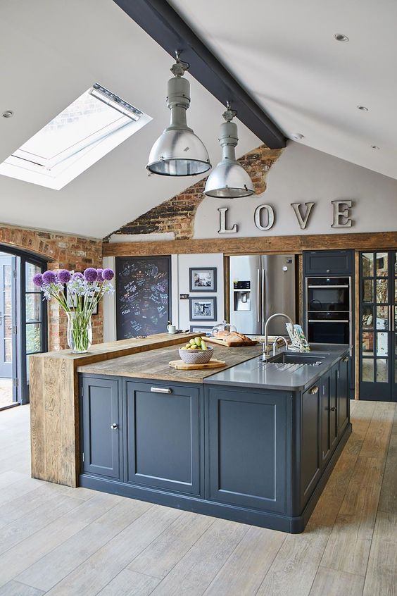 a chic and cool kitchen with blue cabinetry, light brown wooden countertops, brick and concrete countertops