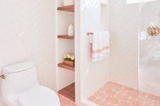 a chic contemporary bathroom with pink printed tiles on the floor, gold touches and fixtures plus simple white tiles on the walls