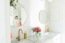 a chic white bathroom with gold pendant lamps, gold handles, fixtures and round mirrors in gold frames