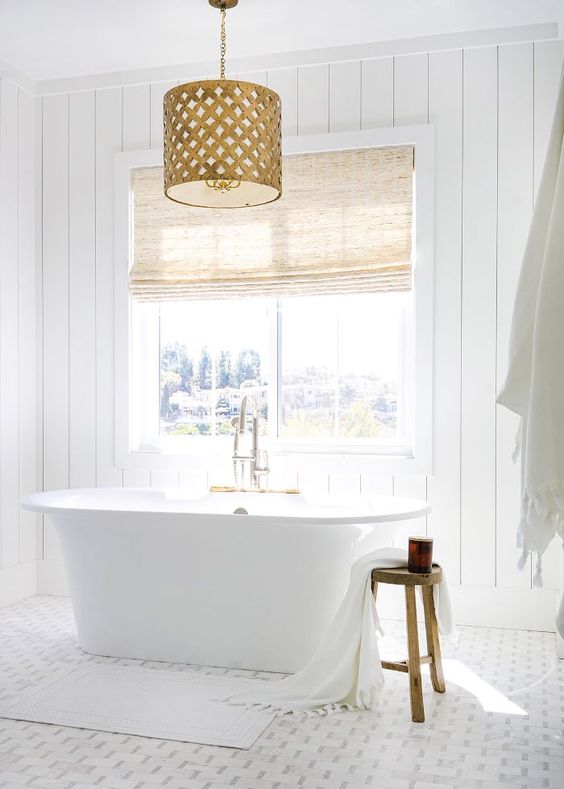 بالصور ديكورات حمامات انيقة باللون الابيض لمنزلك في ربيع 2020 حصري A-chic-white-bathroom-with-shiplap-walls-a-mosaic-tile-floor-a-tub-by-the-window-and-a-fabric-covered-vanity