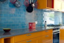 a colorful modern kitchen with yellow cabinets, a blue tile backsplash and touches of bright red for more boldness