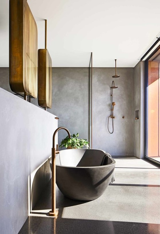 a contemporary bathroom with concrete walls and a floor, a black bathtub, copper fixtures and a glazed wall for more natural light