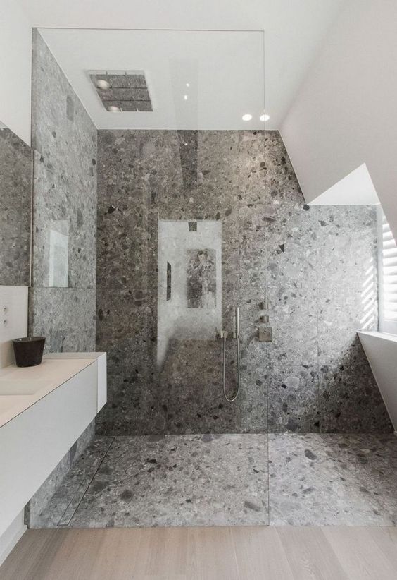 a cool minimalist grey bathroom with grey terrazzo in the shower, a white vanity and windows for natural light