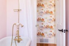 a glam bathroom with light pink walls, gold fixtures and cute floral towels with pink touches