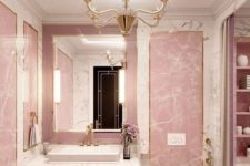 a glam pink bathroom done with stone and marble, with a refined pink vanity, a vintage chandelier and gold fixtures
