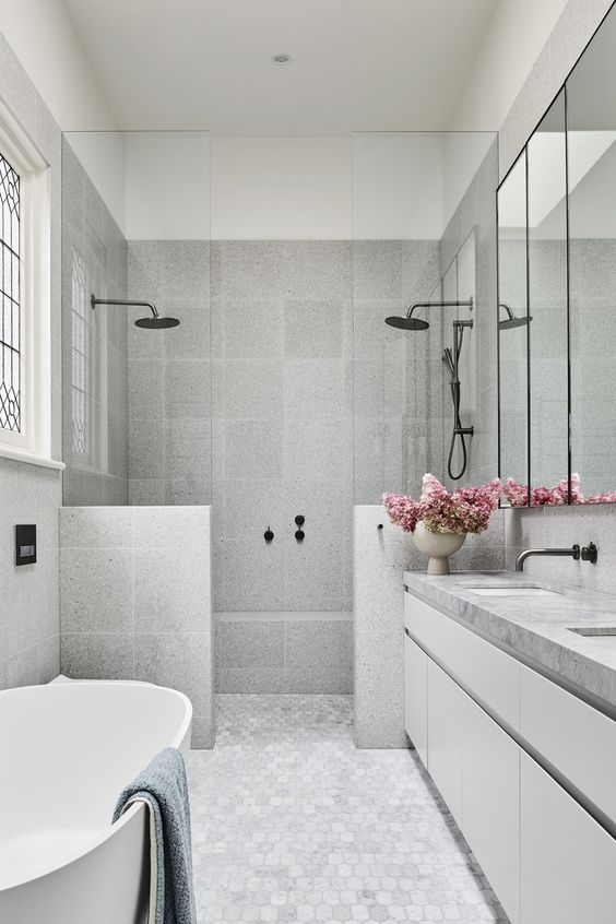 a grey minimalist bathroom with terrazzo tiles and a marble tile floor, a large vanity, a shower and a tub