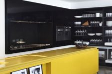 a large contemporary kitchen done with black cabinetry and walls plus a bright yellow kitchen island for a contrast