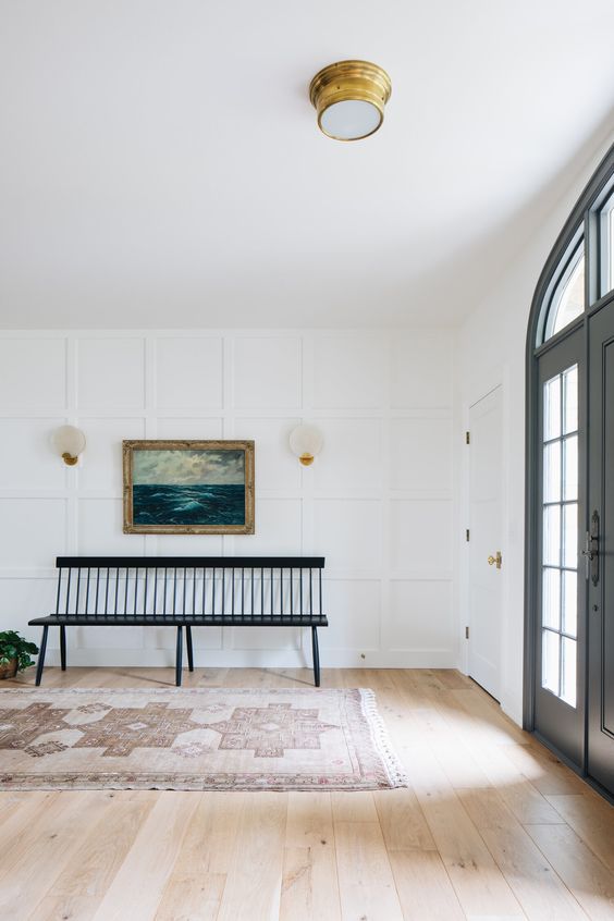 a large entryway with a white accent paneled wall that doesn't look boring but catches an eye and looks chic